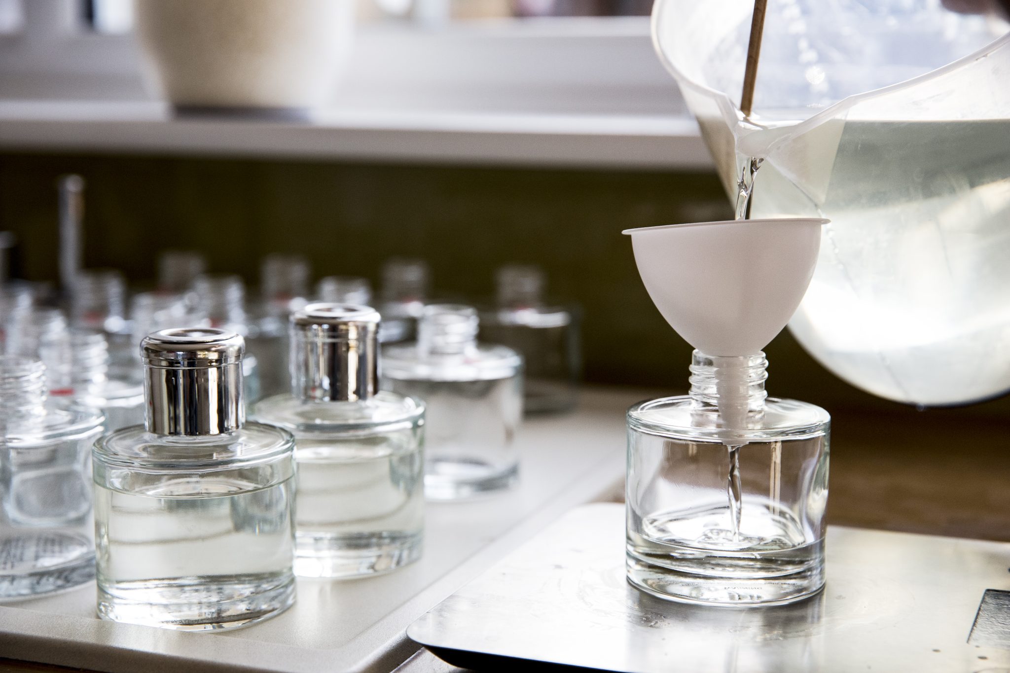 Close up of person pouring liquid for scent diffuser into glass bottle.