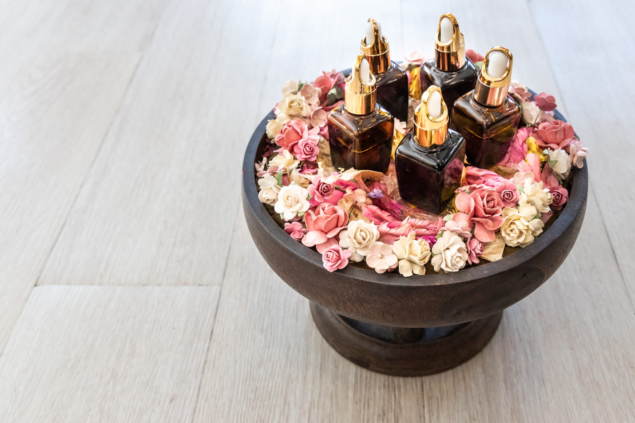 Various essential oil dispenser on tray surrounded with rose petals for massage and spa for complete relaxation